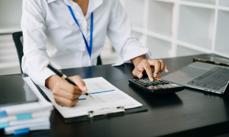 Women counting coins on calculator taking from the piggy bank. hand holding pen working on calculator to calculate on desk about cost