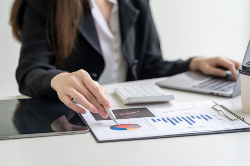 Close-up of a businesswoman hand holding a pen pointing at a chart statistical analysis sitting at the office.