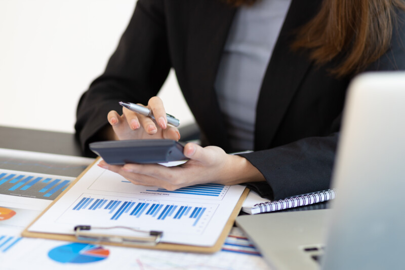 Financial planning and expense accounting concepts. Businesswoman analyzing a business account report using a calculator.